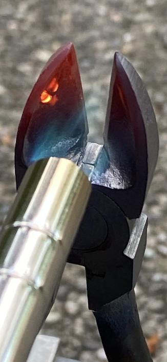 a closeup of the wire cutter when being heated with the left side showing two orange-hot spots… inside it? while the rest is a dull red.