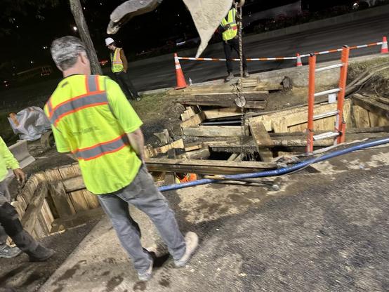 Photo of utility workers and a big hole in the bike path.