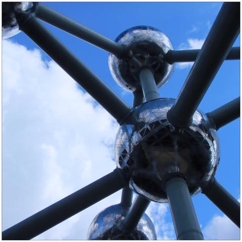 Frog perspective of several aluminum spheres and steel tubes connecting them against a blue sky with white clouds.