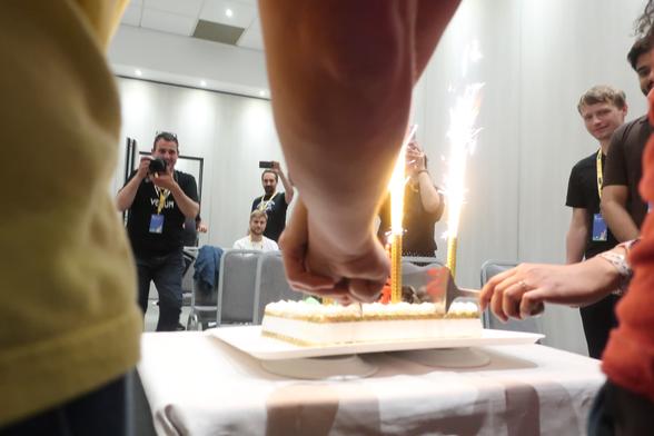 Cake with fireworks is cut by two people holding hands and knife at the same time.