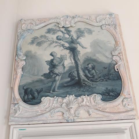 Dessus de porte sur toile en camaïeu de bleu, 18e s. Au milieu,  un arbre, sur lequel grimpe un enfant. Au pied de l'arbre, une jeune fille avec une petite cage. Un autre enfant allongé derrière l'arbre.  À gauche, un chien. Le tout dans son cadre chantourné portant des traces de peinture bleue découverte lors de la restauration et conservées.