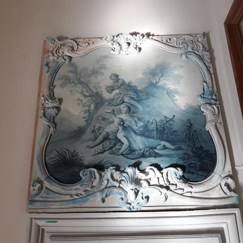 Autre dessus de porte sur toile en camaïeu de bleu, 18e s. Un enfant qui vient de cueillir une grappe de raisin et l'offre à deux jeunes filles dont l'une de dos, nue. Sur le côté à droite, un panier déborde de grappes de raisin. Le cadre porte également des traces de peinture bleue et jaune, découvertes lors de la restauration. 
Le tout dans son cadre chantourné portant des traces de peinture bleue découverte lors de la restauration et conservées.