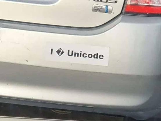 Auf dem Bild sieht man die Stoßstange eines Autos mit einem Aufkleber. Der Aufkleber soll den Satz "I ❤️ Unicode" darstellen. Allerdings ist das Herzsymbol durch ein typisches Unicode-Ersatzzeichen (ein schwarzes Rautensymbol mit einem Fragezeichen) ersetzt, weil das Herzsymbol nicht als Unicode-Zeichen dargestellt werden konnte.