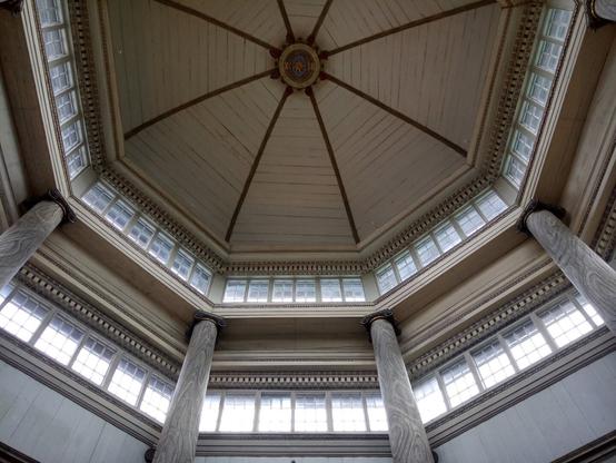 An octagonal cupola seen from the inside. The ceiling, walls and pillars are wood painted in light grey. There are two rows of windows to let as much daylight as possible in; this cupola was built to be the light inlet for an anatomical theatre.