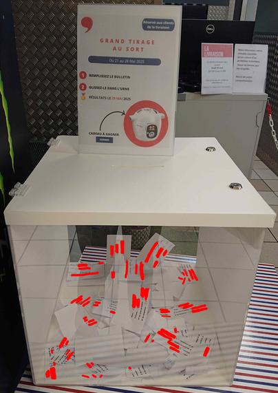 Photographie d'une urne transparente prise dans un magasin Monoprix. Au-dessus, une pancarte annonce un tirage au sort pour gagner un cadeau. À l'intérieur de l'urne, on distingue un tas de bulletins, déposés tels quels, sans enveloppes, exposant ainsi le nom, prénom, numéro de téléphone et numéro de carte de fidélité d'un certain nombre de clients. Ils ont été censurés.
