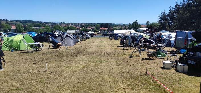 Une allée d'herbe coupée bordée de bivouacs et d'instruments d'observation sous un chaud soleil