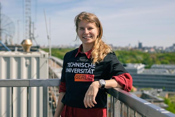 Rabea Rogge steht auf dem Dach des Hauptgebäudes der TU Berlin und trägt ein T-Shirt mit der Aufschrift "Technische Universität Berlin". Foto: Kevin Fuchs