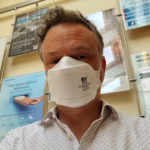 Man wearing FFP3 mask in a GP waiting room.
