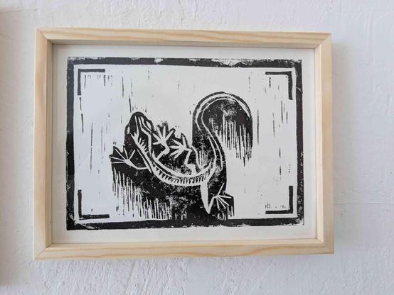 A monochrome linocut print featuring a lizard.