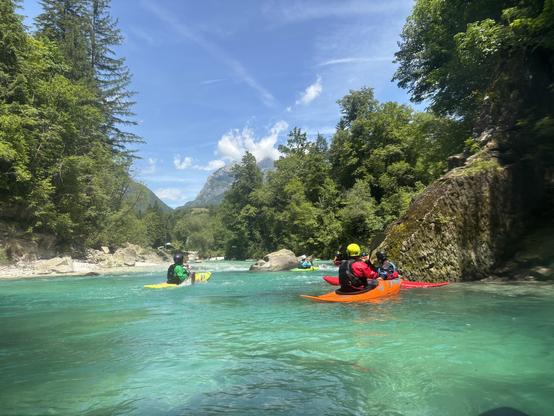 Two kayakers on a turquoise river. Their boats and equipment are very colorful, and the water is so clear that it’s almost transparent