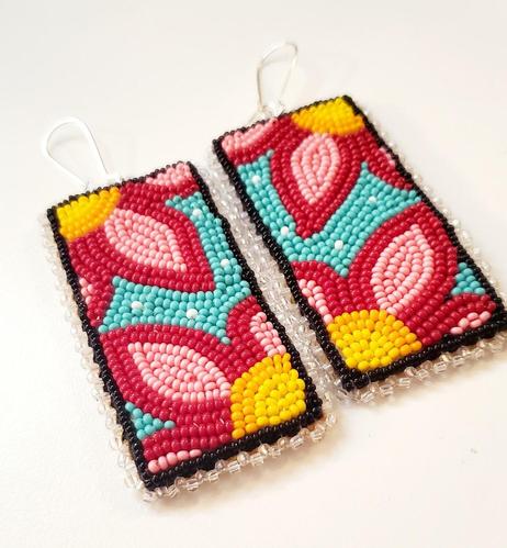 a pair of beautiful beaded panels by kiamichi as dangling earrings depicting flowers in pink and yellow on a teal background