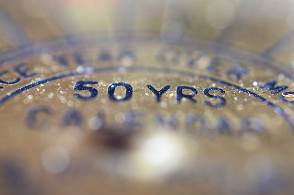 A macro photograph of the brass face of a fifty year calendar.