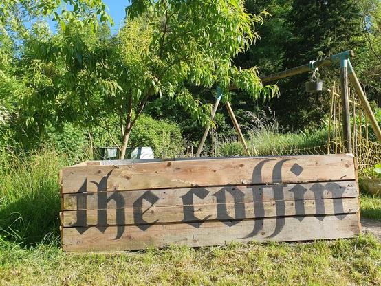 Rustic raised wooden flowerbed with the words the coffin painted in blackletter on the side