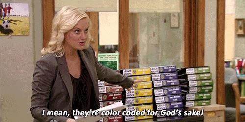 Leslie Knope from the tv show Parks and Rec proudly pointing to her gigantic pile of binders of notes