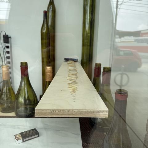 Several wine bottles, a pack of matches, and a lineup of a chips ordered by size are displayed near a window.
