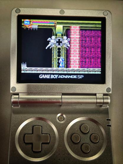 My handheld device displaying the game. The screen shows the main character (a guy wearing a white coat) standing, the place is blocked off by a brick wall