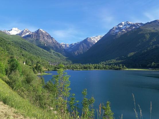 Vue sur le lac de Genos-Loudenvielle.

On voit le lac au premier plan, et derrière le fond de la vallée du Louron verte là où elle est couverte d'arbres, et des sommets enneigés en arrière-plan.