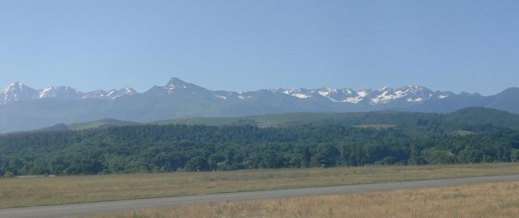 Vue sur la chaîne des Pyrénées. Au premier plan une forêt, et derrière, les sommets des Pyrénées vus depuis Tarbes.