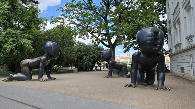 Drei gesichtslose überlebensgroße Baby-Figuren krabbeln über einen Platz. #Kunst