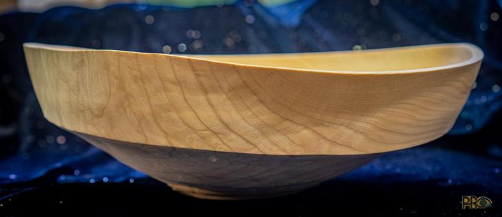 A wooden bowl in an almost white color photographed against a dark blue background. The shape is not left round, rather sharp at the edges and crooked from the drying process. Looks more like a ship.
🇸🇯En dreid trebolle nærmere hvit farge fotografert mot mørk blå bakgrunn. Fasongen er ikke levnt rund, heller skarp i kantene og skjev fra tørkeprisessen. Ser mer ut som en skute på sjøen.