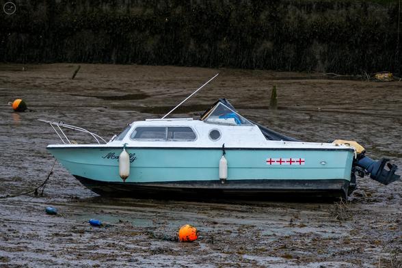 turquoise small boat at rest in muddy low water harbour