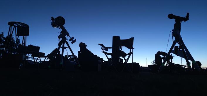 Un crépuscule magnifique, des instruments d'observation en ombre chinoise, un observateur assis, les yeux vers le ciel.