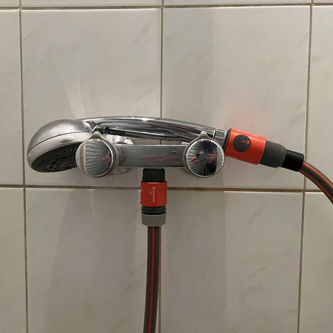 A Grohe shower head is connected to the two knob shower faucet using two orange Gardena quick connectors and an orange Gardena hose