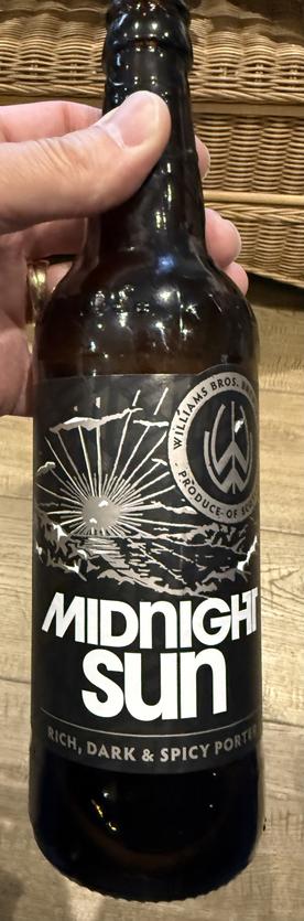 A tall black bottle with white lettering and a sunburst pattern