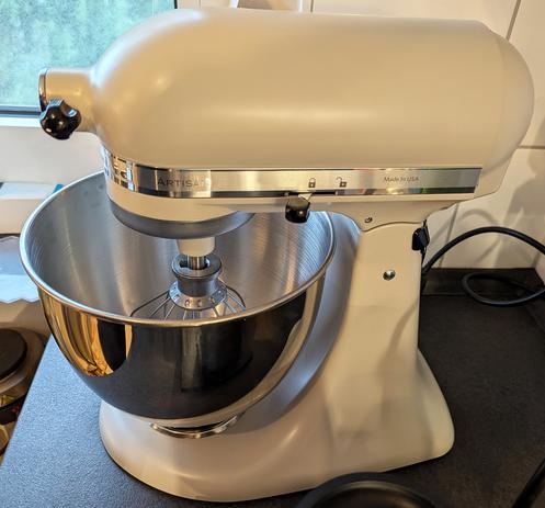 A side view of my new KitchenAid Artisan stand mixer in the color "Milkshake" (which is beige) with a stainless stell mixing bowl and a wire whisk attached