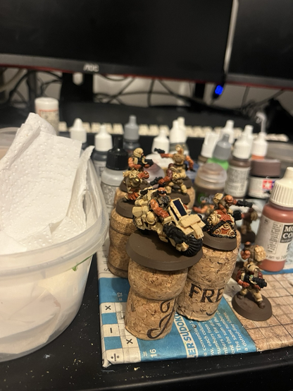 Some partially painted desert dwarf minis on a painting table.