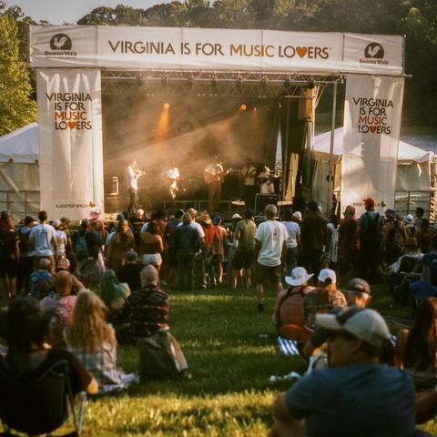 Town Mountain, alt country band performing on lakeside stage at magic hour, crowd on hill in foreground