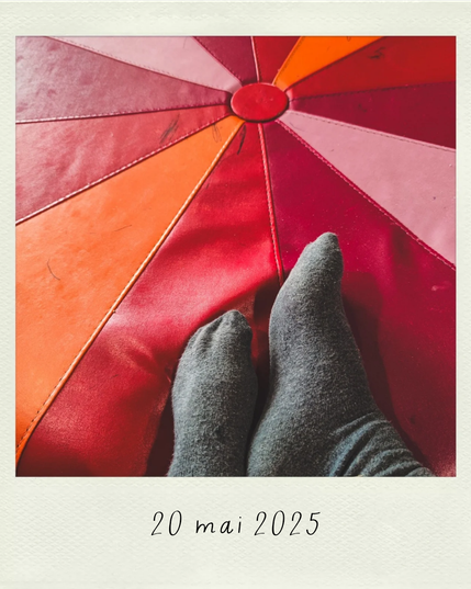 mes pieds en chaussettes grises sur un pouf géant aux rayons de couleurs