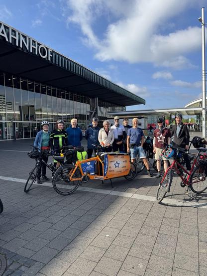 Eine Gruppe Fahrradfahrer und das Staffelrad des ADFC vor dem Hbf Braunschweig