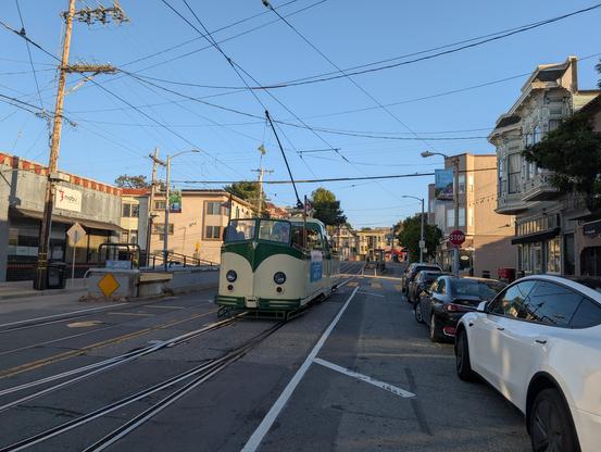 Muni's Boat Tram, returning to the yard via the Church Street line with several passengers aboard.  It's open-topped and shaped somewhat like a boat, and flies a Union Jack on a short flagpole.