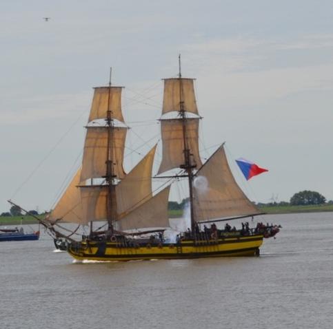 Nachbau eines zweimmastigen Segelschiff aus dem 18. Jahrhundert auf einem Fluss. Die Segel sind gesetzt.