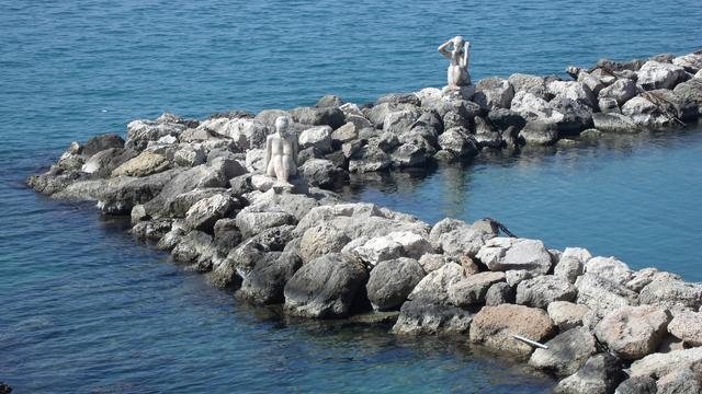 A breakwater, with two nude statues on it.