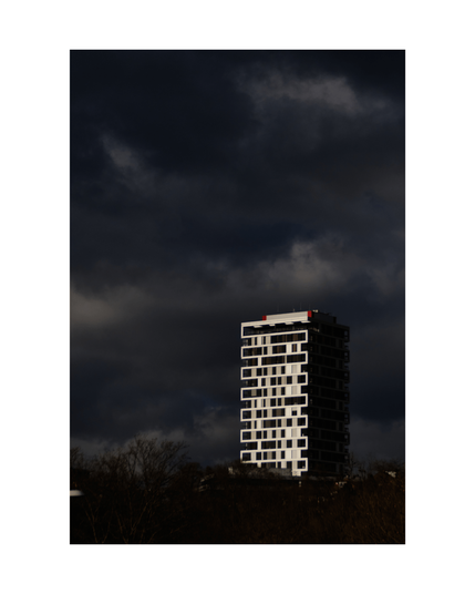 metallic shiny tall building atop a dark hill with black trees, dark sky with massive clouds above