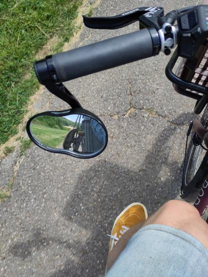 Photo d'un rétroviseur de vélo prise en roulant (ne faite pas ça chez vous) dans lequel on voit le skateboard fixé sur la structure arrière du vélo.