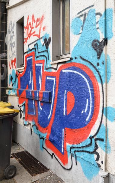 Blaue Schrift 1 UP mit oranger Kontur an einer Hauswand.