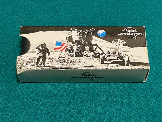Original carton for Fisher space pen ... depicting a LEM, a lunar rover and a suited-up astronaut saluting in a lunar landscape.