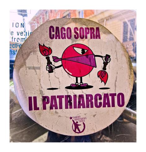 The photo is of a sticker with a cartoon illustration of a round, pink character wearing a bandana over its mouth and holding two Molotov cocktails. The character has an angry face. Above and below the character there is text in Italian that reads:
"CAGO SOPRA IL PATRIARCATO"
Or "I shit on the patriarchy" in English. At the bottom, there is a logo with the name "Studenti Indipendenti Statale" a student group here in Italy.