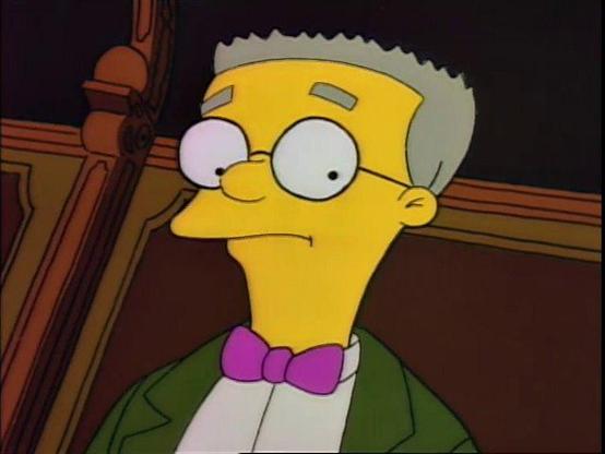 screengrab of "Mr Smithers" character from the simpsons, grey haired man with glasses and bowtie, standing and looking concerned in a wood paneled room