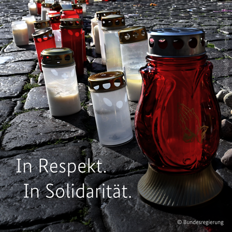 Grablichter und Kerzen stehen auf dem Marktplatz in Mannheim. Davor die Wörter: In Respekt. In Solidarität.