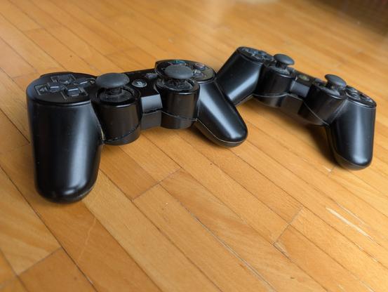 Zwei Controller für die PlayStation3. Bei beiden wirkt es, als würden die obere und untere Hälfte von innen auseinander gedrückt.