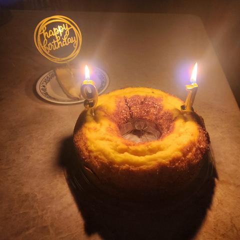 A piece of key lime pie with a gold plastic "Happy Birthday" topper and a Louisiana crunch cake with lit gold "9" and "1" candles