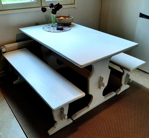 A white country style table with two long benches in a kitchen.