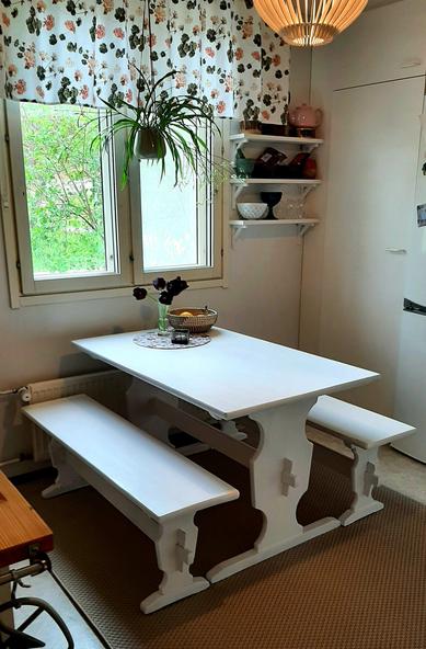 An overview of the kitchen with the table and chairs and wall shelves next to the window.