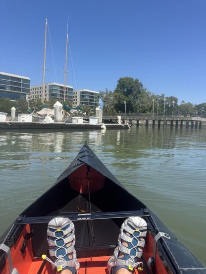 My feet in a kayak with some buildings in the background