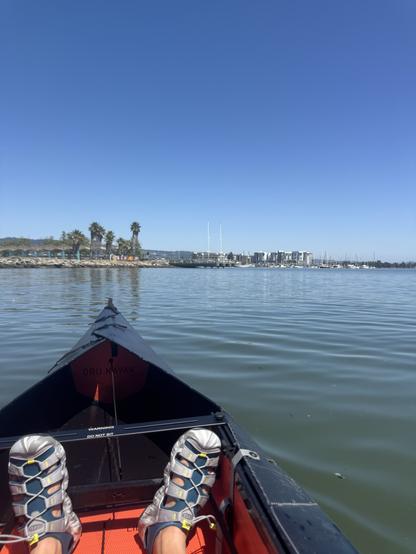 My feet in a black kayak with some trees in the background
