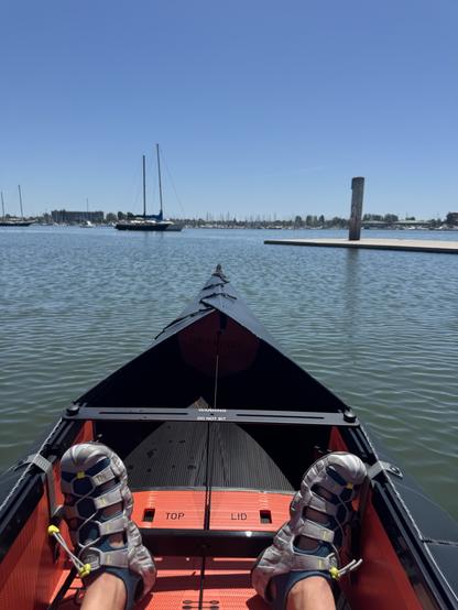 My feet in a kayak with some boats in the background